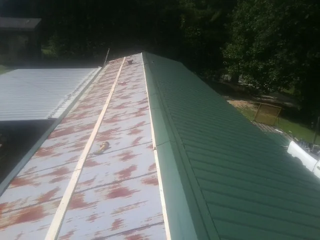 Old rusted panels beside newly installed green metal roofing — Wind Damage Roof Repair by Roofing Brothers in Sumterville