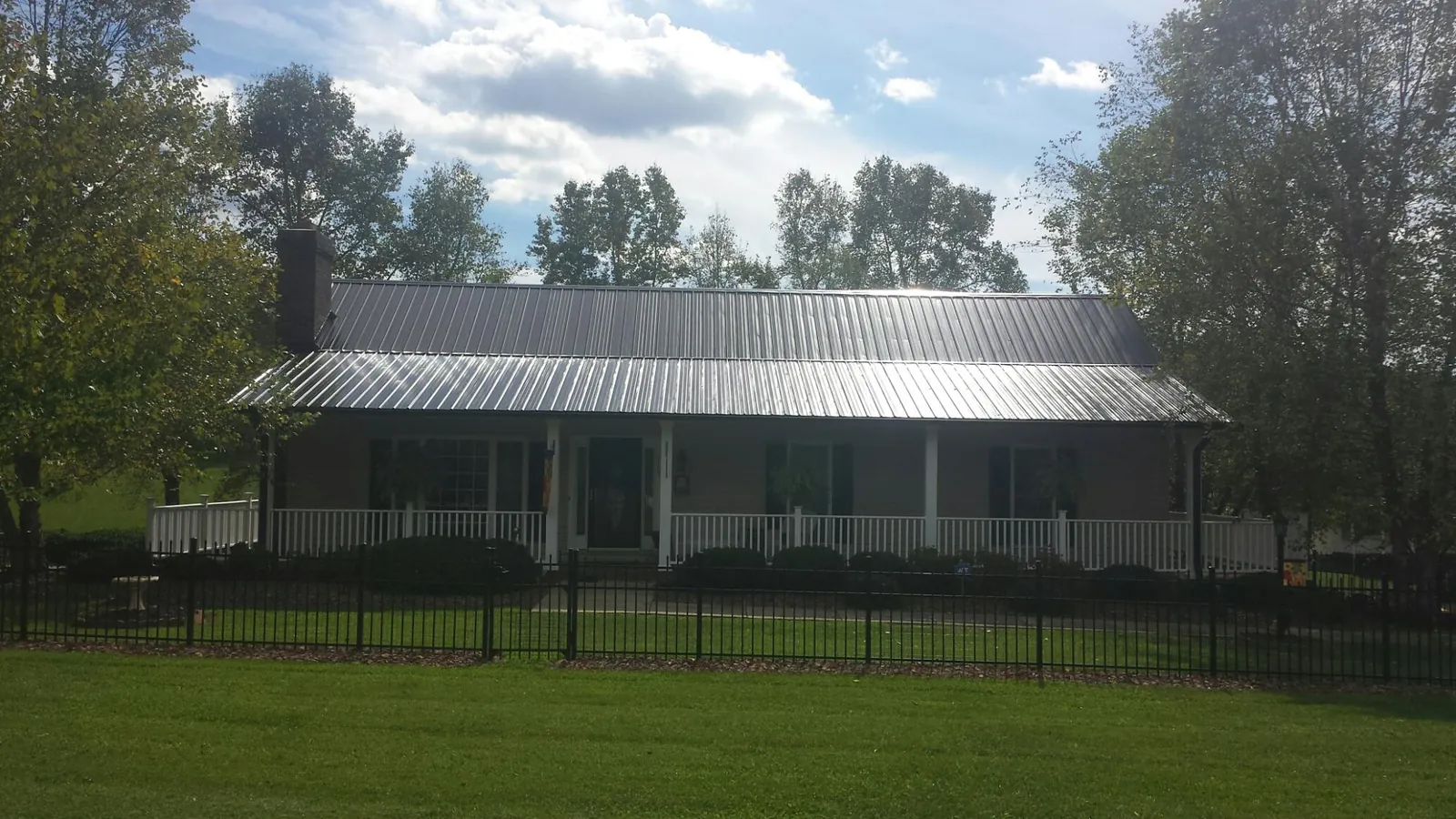 Gray metal roof on a brick ranch with a full width front porch — Gutter Guard Installation work by our crew in Sumterville