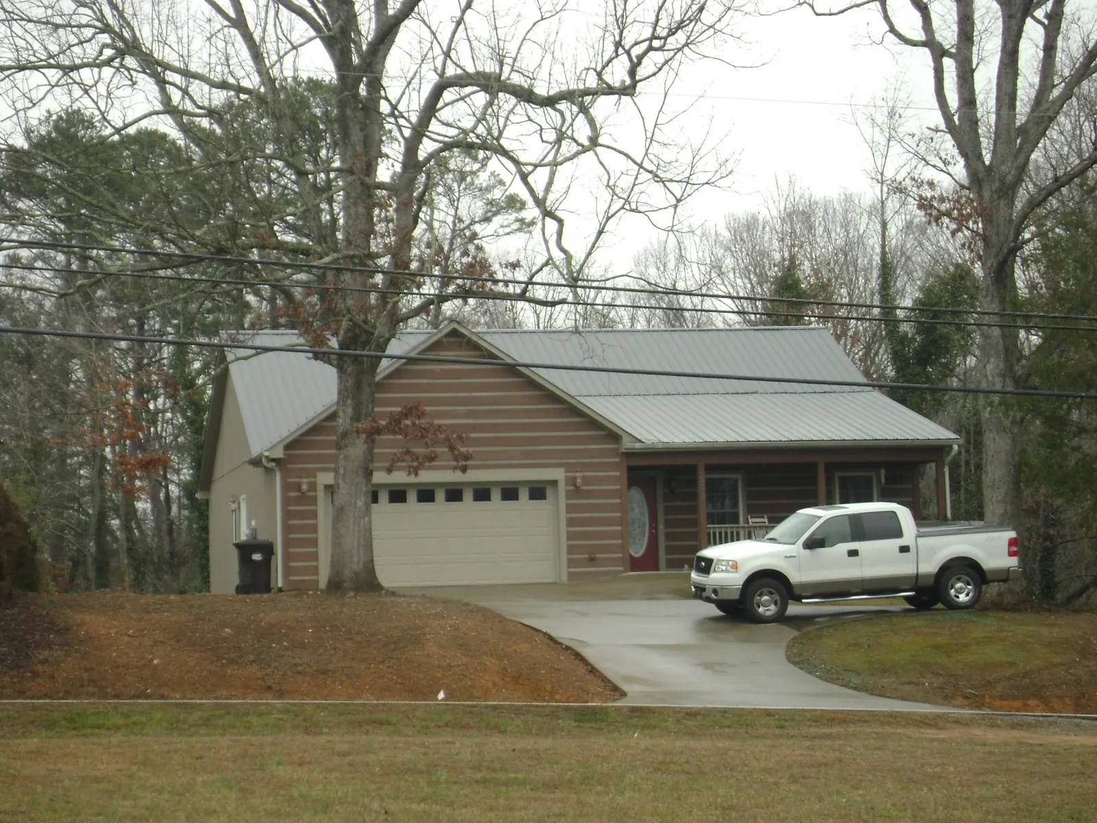Gray metal roof on a log sided house with an attached two car garage in Sumterville