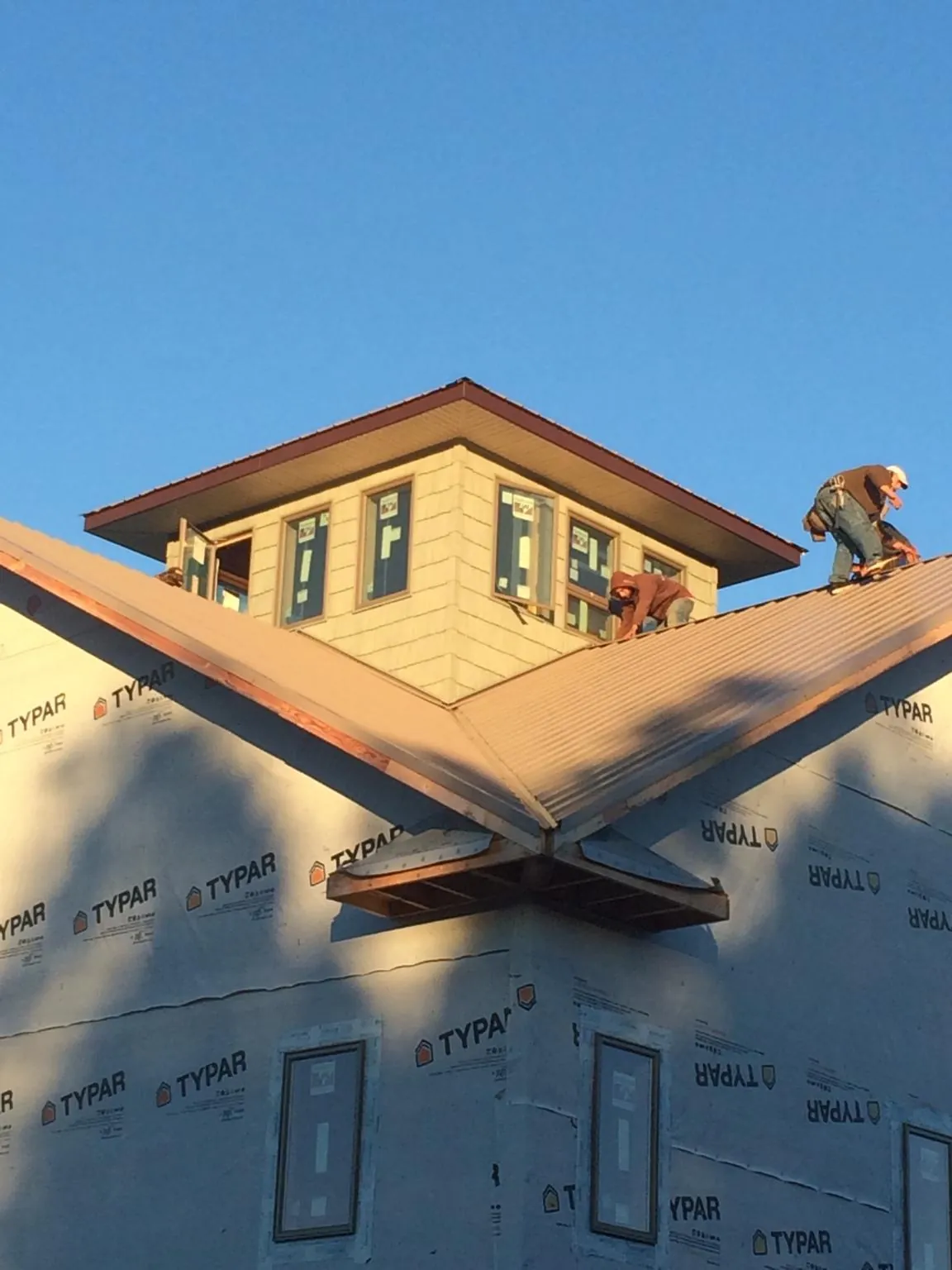 Roofers working around a rooftop cupola on a new metal roof at sunset — Roof Waterproofing in Sumterville by Roofing Brothers